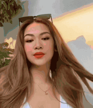 a woman wearing sunglasses and a necklace is looking at the camera .