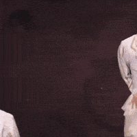 a man with black hair and a white shirt is holding his finger to his lips
