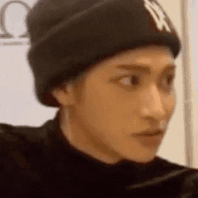 a close up of a person wearing a black beanie and making a funny face .