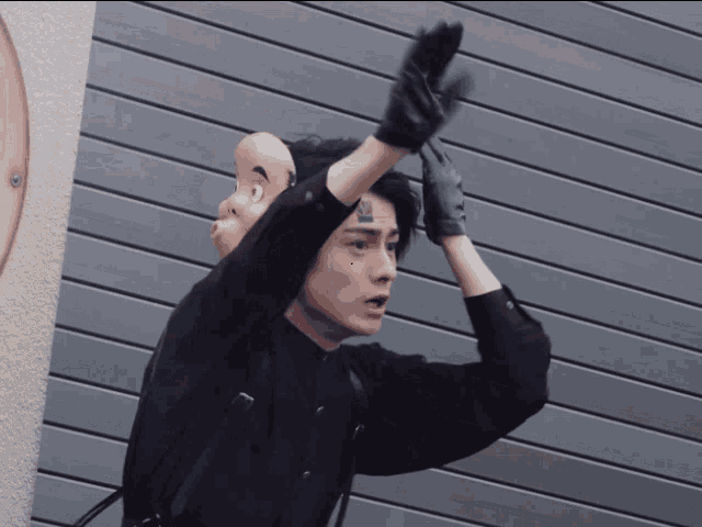 a man wearing a black shirt and black gloves has a tattoo on his face