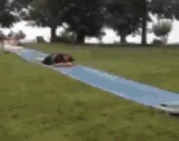 a person is laying on a blue slide in a park