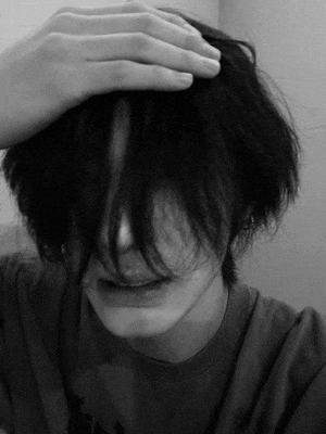 a black and white photo of a person with their hand on their head .