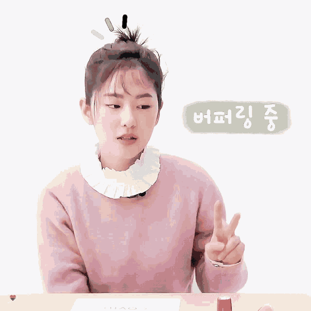 a girl in a pink sweater has a bun on her head and a green sign that says ' xiao ' on it