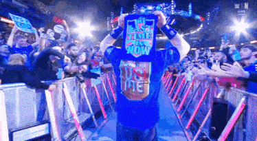 a wrestler wearing a blue shirt that says the last time is now walks through a crowd