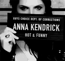 a woman is holding up a sign that says anna kendrick hot and funny