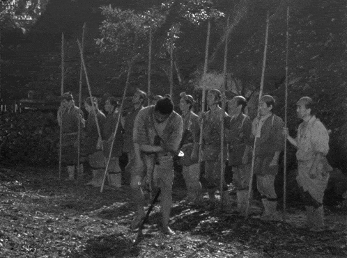 a black and white photo of a group of people with sticks
