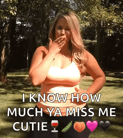 a woman is blowing a kiss while standing in a park .