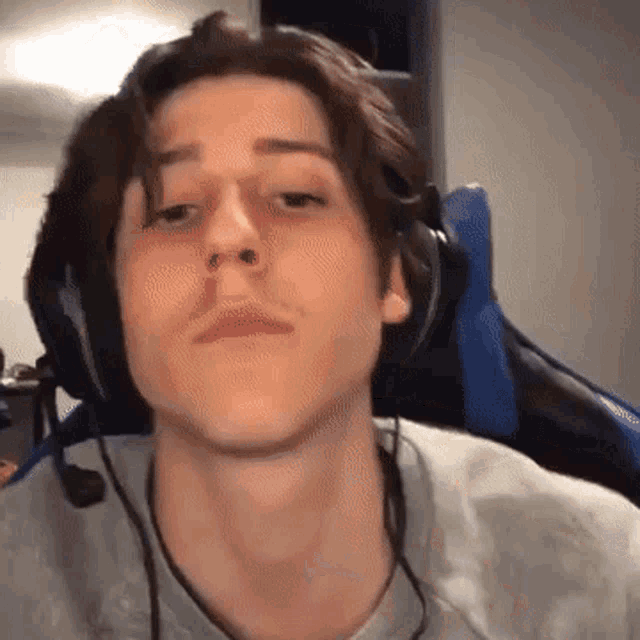 a young man wearing headphones is sitting in a gaming chair .