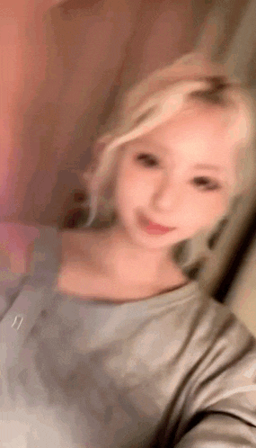 a woman with blonde hair is taking a selfie in a room .