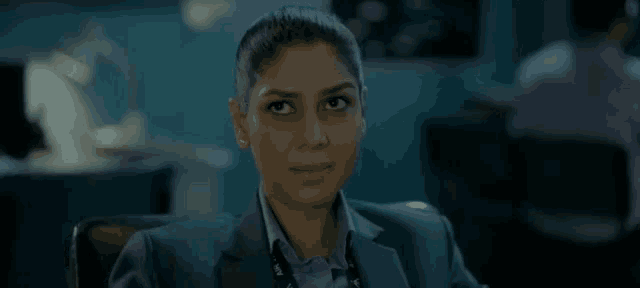a woman in a suit is sitting in a chair in a dark room .