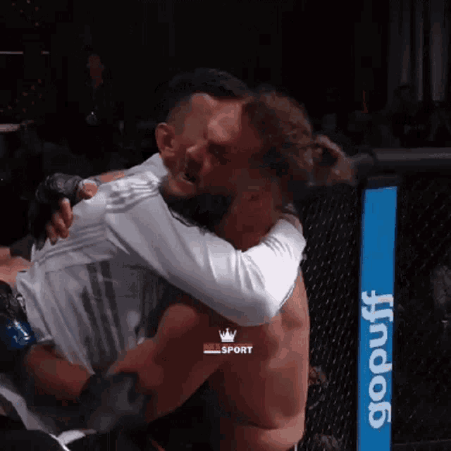 a man is hugging another man in a boxing ring with a gopuff sign in the background