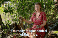a woman in a red dress is sitting in the woods and says i 'm ready to take control of this tribe