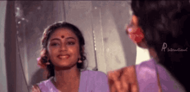 a woman is looking at herself in a mirror and smiling