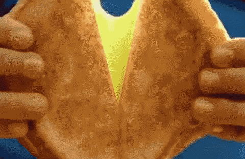 a close up of a person holding a sandwich with cheese