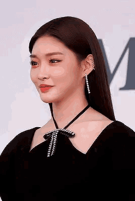 a woman is wearing a black dress and earrings .