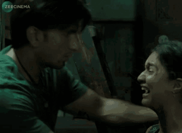 a man in a green shirt is holding a woman 's neck in a scene from a movie that is sponsored by zeecinema