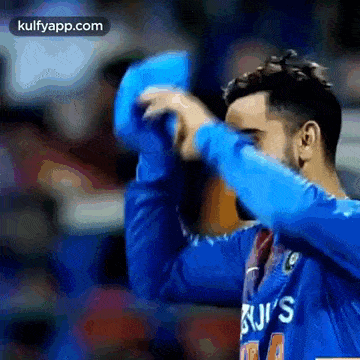 a man in a blue shirt is holding a blue object in his hand .