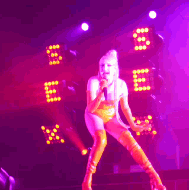 a woman singing into a microphone while wearing thigh high boots