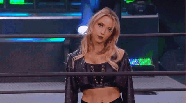 a woman is standing in a wrestling ring looking at the camera
