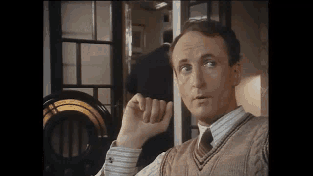 a man in a sweater vest and tie is talking