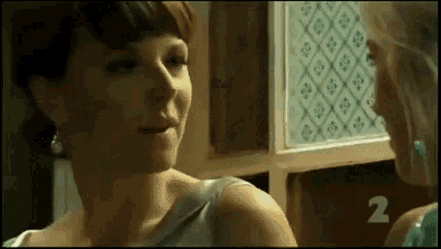 two women are standing next to each other and talking to each other in a room .