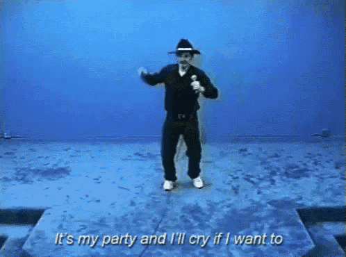 a man in a hat is singing into a microphone while dancing on a stage .