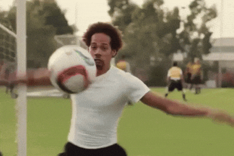 a man in a white shirt is kicking a soccer ball on a field