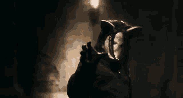 a person in a mask is talking on a phone in the dark .