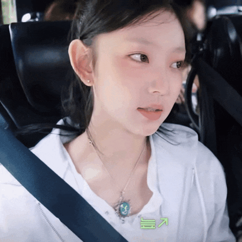 a woman wearing a white shirt and a blue seat belt looks at the camera