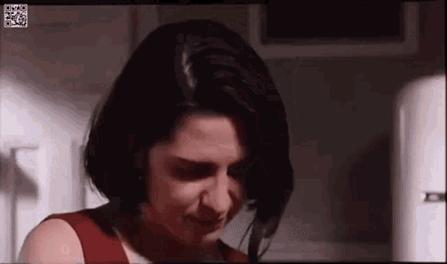 a woman in a red dress is standing in front of a refrigerator and crying .