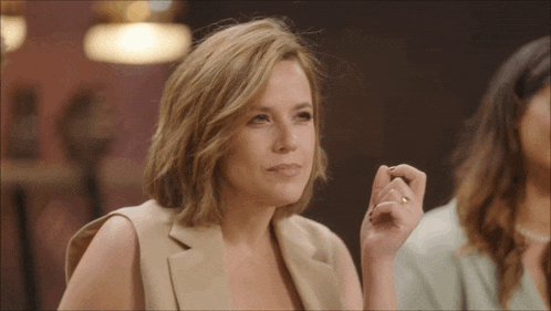 a woman with a gold ring on her finger looks at the camera