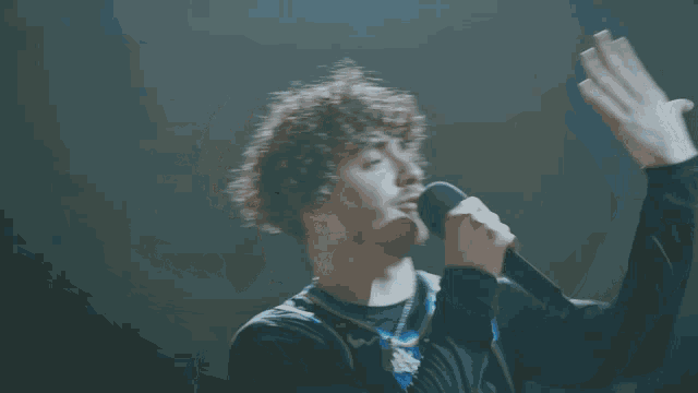 a man with curly hair is singing into a microphone and wearing a jersey that says thunder