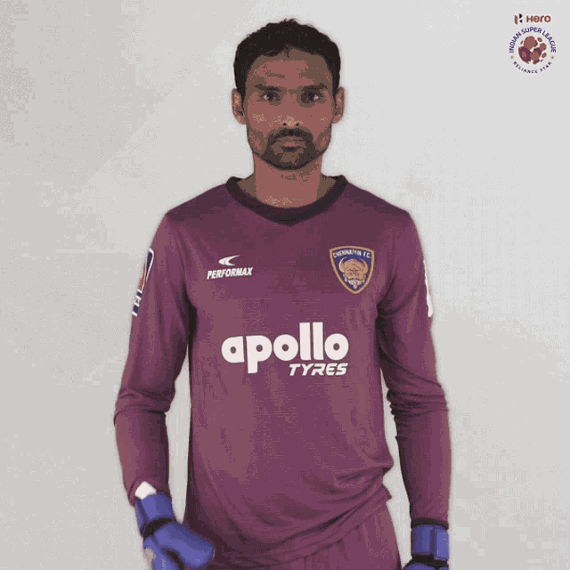 a man wearing a purple apollo tyres jersey holds up his hand