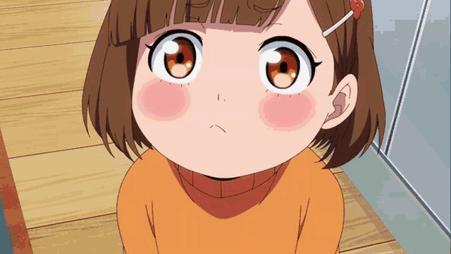 a little girl with brown hair is wearing an orange sweater and has a red ribbon in her hair