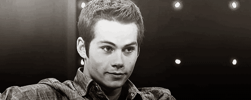 a black and white photo of a young man wearing a plaid shirt and looking at the camera .