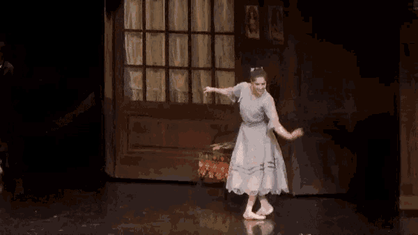 a ballerina is dancing on a stage in front of a door