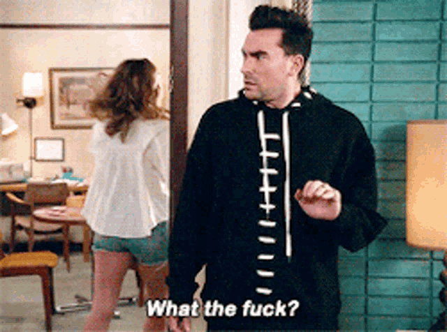 a man in a black hoodie is asking a woman what the fuck