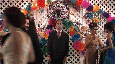 a man in a suit and tie is standing in front of a colorful wall with a sombrero on it