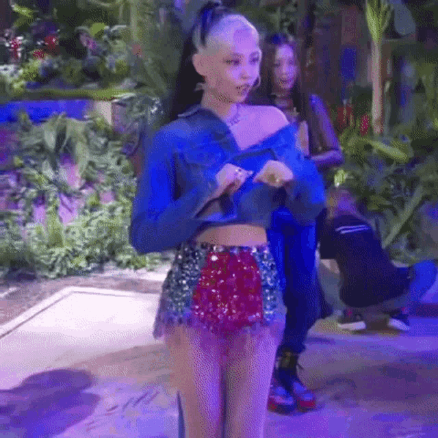 a woman in a crop top and shorts is standing on a stage in front of a purple light .