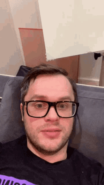 a man with glasses is sitting on a couch