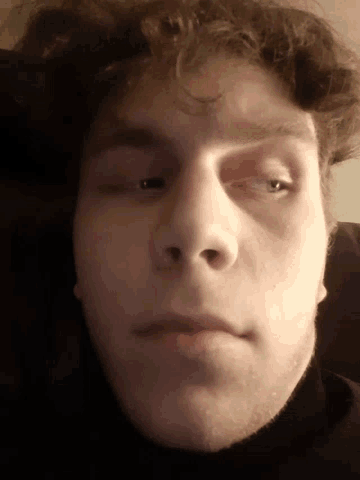 a close up of a man 's face with a beard and curly hair