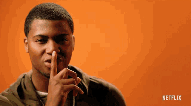a man holds his finger to his mouth with a netflix logo in the corner