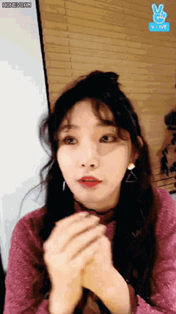 a girl is giving a peace sign in front of a vlive sign