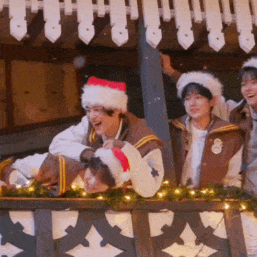 a group of people wearing santa hats and jackets are laughing