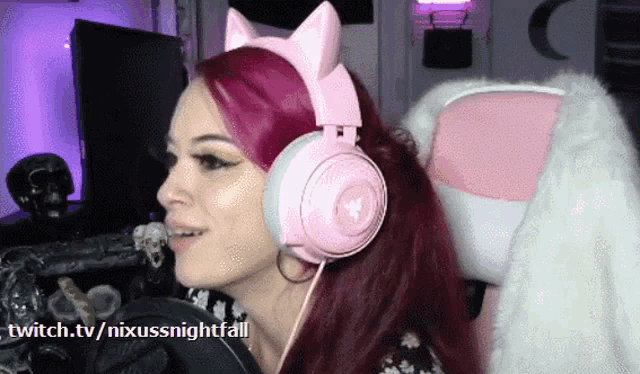 a woman wearing a pair of pink cat ear headphones is sitting in a pink chair