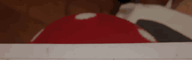 a red ball with white spots on it is sitting on a white surface