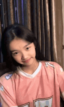 a young girl is wearing a pink shirt and smiling .