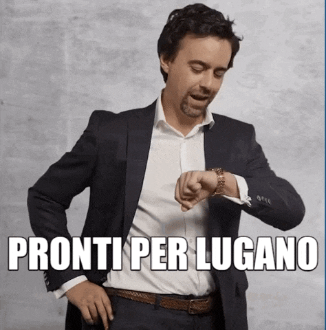 a man in a suit looks at his watch with the words pronti per lugano written below him