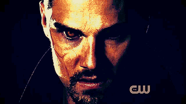 a close up of a man 's face with a cw logo on the bottom
