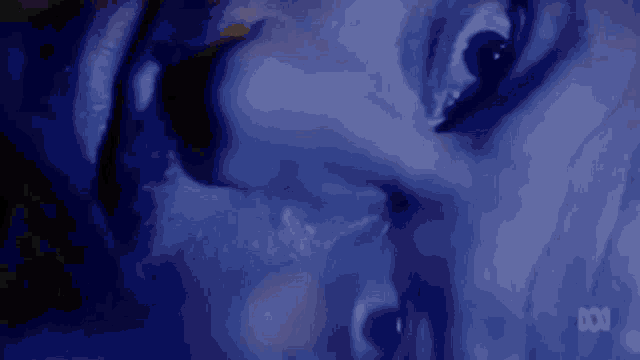 a close up of a person 's face in a dark room in a blue light .